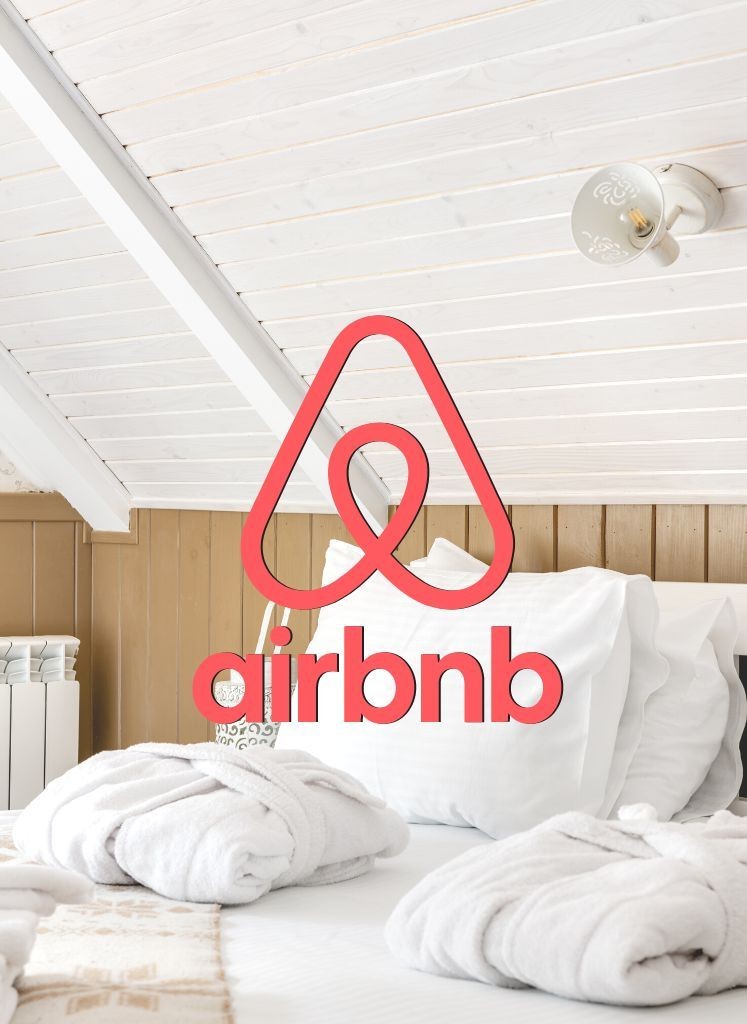 Attic bedroom with cozy white linens, towels on bed, and Airbnb logo overlay.